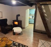 The interior of a cabin with a fireplace, an armchair, and a wooden-patterned floor.