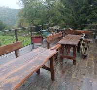 Wooden benches and tables on the terrace with a view of the forest near the cottage in Píla.
