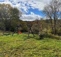 A swing on a grassy area near a cottage in Píla, surrounded by autumn nature.