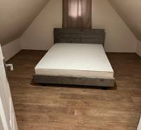 Attic room in a cottage with a bed and a wooden decor floor.