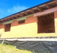 An unfinished family house in Hokovce with a brick structure and a roof with wooden beams.