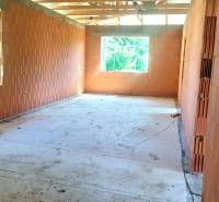 An unfinished interior in a family house under construction with brick walls and large windows.