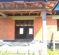 Unfinished family house in Hokovce with unplastered brick walls and exposed roof structure.