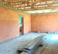 An unfinished construction of a family house with bricks and wooden beams.