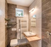 A bathroom in a family house with dark tiles and a wooden decor floor.