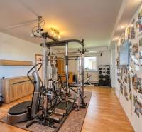 A room in a family house with fitness equipment and a wall full of photographs on a floor with wooden decor.