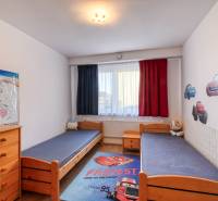 Children's room in a family house with separate beds, wooden furniture, and car decorations.