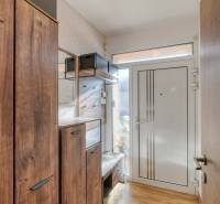 The hallway in the family house contains a wardrobe, a shoe cabinet, and a floor with a wooden decor.