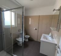 Bathroom in a 3-room apartment with a glass shower, sink, and toilet.