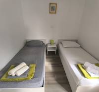 A bright bedroom in a 3-room apartment with two single beds and a wooden decor floor.