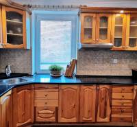 A kitchen in a family house with wooden cabinets and a tiled floor.