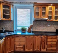 A kitchen in a family house with wooden cabinets and a dark countertop.