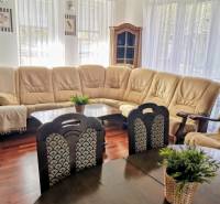 Living room with a cream sofa, wood-patterned floor, table with flowers.