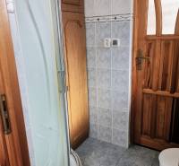 Bathroom in a family house with a tray shower, light tiles, and wooden details.