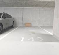 Parking spot number 143 in the garage with a gray car and a cardboard box.