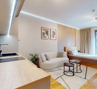 A one-room apartment with a wooden decor floor, a kitchen, and a comfortable bed.