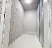 Storage space in a studio apartment with concrete walls and metal doors.