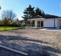 A family house with a garden on flat terrain, surrounded by greenery and trees.