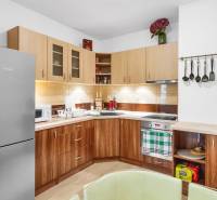 A kitchen in a 2-room apartment with a wood-patterned floor and white walls.