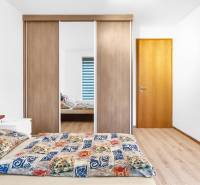 Bedroom with a double bed, built-in wardrobe, and wood-patterned flooring in a 2-room apartment.