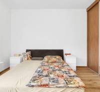 Bedroom with a bed, nightstands, mirrored wardrobe, and wooden decor flooring in a two-room apartment.