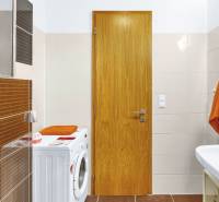 A bathroom with a washing machine and a sink in a 2-room apartment, with orange accessories.