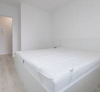 A bright bedroom with a bed and a wood-decor floor in a two-room apartment.