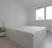 A bright bedroom with a bed and wood-decor flooring in a 2-room apartment.