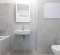 A bathroom with a shower, sink, and toilet in a 2-room apartment with tiled flooring.