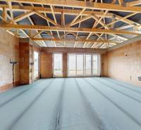 The interior of a house under construction with exposed brick walls and roof structure.