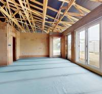 Construction of a family house with a roof structure and large windows without surface finishes.