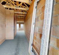 An unfinished interior of a family house with brick walls and wooden roof beams.