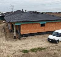 Construction of a family house in Bernolákovo with exposed bricks and parking on dirt.