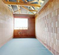A room in a family house with brick walls and an unfinished floor.