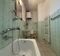 A bathroom in a family house, with a bathtub, sink, toilet, and light green tile decor.