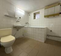 Bathroom with white tiles, a toilet, and a bathtub in a family house.