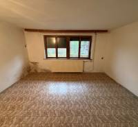A room in a family house with a wooden decor floor and a window, slightly damaged walls.