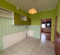 A kitchen in a family house with tiles, green walls, and wall cabinets.