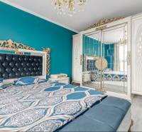 A bedroom in a family house with a turquoise wall, a mirrored wardrobe, and a decorative chandelier.