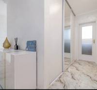 Interior of a family house with white furniture and a marble-patterned floor.