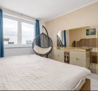 A bedroom in a family house with a bed, a wardrobe, and blue curtains.