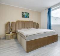 A room with a bed, beige tones and a painting, a floor with a wooden decor.
