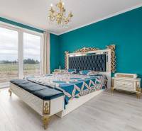 Luxurious bedroom with ornamental furniture, chandelier, and large window in a family house.