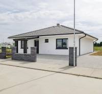 A family house in Hrubá Borša with a white facade and a dark roof, brick fencing.