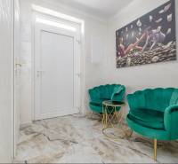 Interior of a family house with white walls, emerald armchairs, and a painting on the wall.