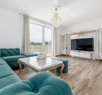 A spacious living room in a family house with a corner sofa and a wooden-patterned floor.