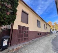 A family house in Bratislava-Rača with a garage and a tree by the road.