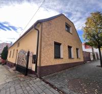 A house in Bratislava-Rača with a sloped roof, interlocking pavement, and trees along the walkway.