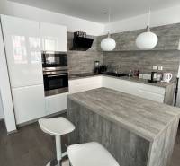 A kitchen in a 2-room apartment with a kitchen island and a floor with a wooden decor.