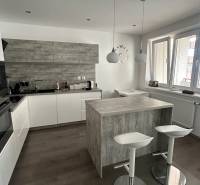 A kitchen with seating, white cabinets, and wood-patterned flooring in a 2-room apartment.